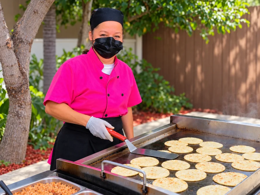 Gloria cooking fresh corn tortillas on an outdoor plancha