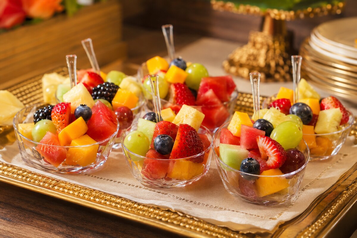Individual bowls of colorful seasonal fresh fruit with mini forks